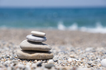 Round stones lie on top of each other in a column on the seashore on a sunny summer day. The concept of order and tranquility