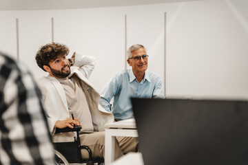 Smiley, good looking, mature businessman listening to a presentation at the classroom with his...