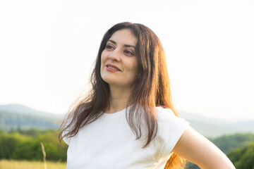 Fototapeta premium Portrait of a pensive 35-year-old woman in a white T-shirt against the sky in nature in summer.