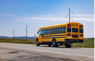Fototapeta na wymiar Autobus scolaire de dos, ciel bleu, rural, horizontal