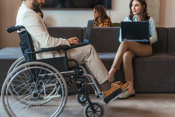 Disabled business person in wheelchair working on lap top. Side photo