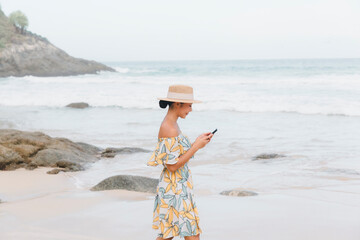 A happy woman walks on the beach, engrossed in a phone call, effortlessly combining the joy of...