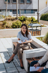 Attractive brunette woman laughing during random conversation with her colleagues while taking a break