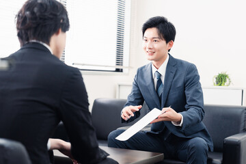商談で書類を提示するビジネスマン