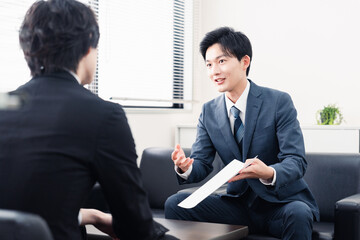 商談で書類を提示するビジネスマン