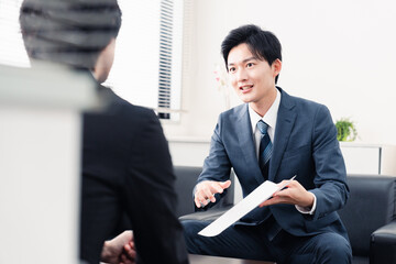 商談で書類を提示するビジネスマン