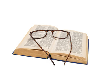 An old, open dictionary with glasses on it, isolated on a white background.