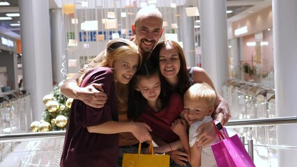 Portrait of a big happy family in a shopping mall with shopping bags, mom and dad hugging three children.