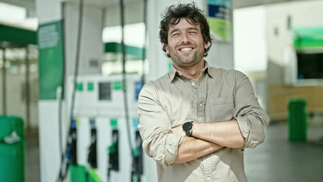 Young hispanic man smiling confident standing with arms crossed gesture at petrol station