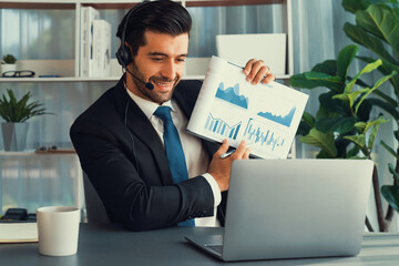 Business man wearing headphone present financial data or BI paper via laptop during online meeting. Remote work concept with virtual meeting presentation of effectiveness remote work. Fervent