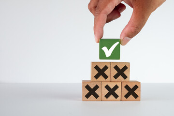 Hand picking Green Wooden cube with check mark(correct ) icon among wooden cubes with wrong icon...