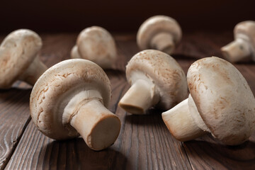 Fresh champignon mushrooms on wooden table, closeup.