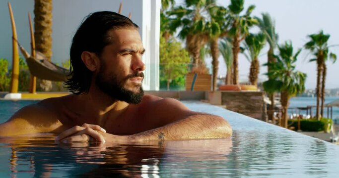 A beautiful view of a pool with an attractive man relaxing.
