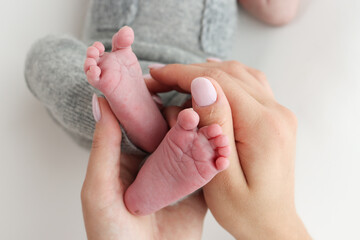 The palms of the father, the mother are holding the foot of the newborn baby on white background. Feet of the newborn on the palms of the parents. Photography of a child's toes, heels and feet.