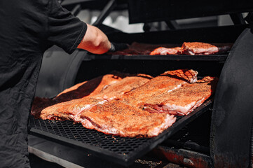 Chef hand cooking grilled pork meat in BBQ smoker.
