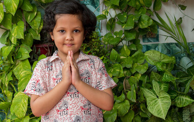 Indian girl holding palms together in Namaste gesture . Smile and looking at camera , welcome...