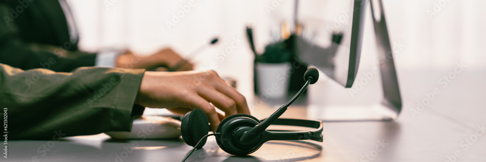 Aufkleber panorama focus hand holding headset on call center workspace desk with blur background of operator t
