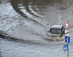 Kyiv, Ukraine - July 7, 2023: A car passes through a flooded road area after heavy rain
