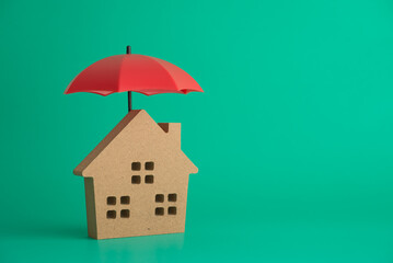 Red umbrella cover home model on green background copy space. House, real estate, property...