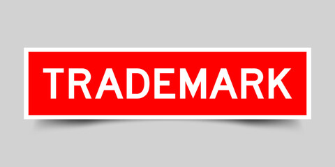 Red color square shape sticker label with word trademark on gray background