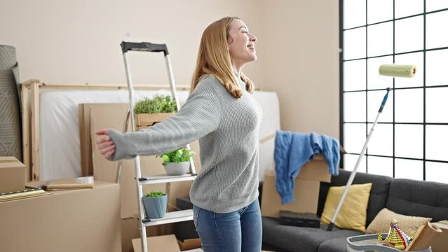Young blonde woman smiling confident turning by herself at new home