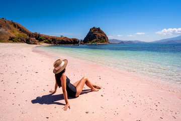 Fototapeta na wymiar Young female tourism enjoying the tropical pink sandy beach with clear turquoise water at Komodo islands in Indonesia