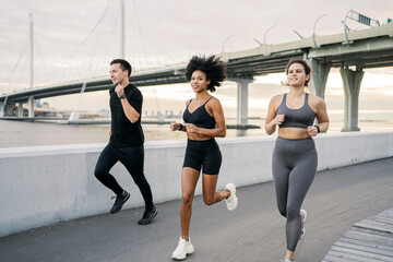 Friends fitness running together workout in the city. Sports people enjoy sports in comfortable clothes and sneakers.