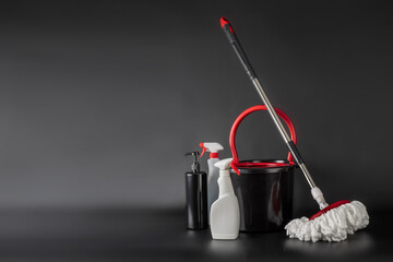 Cleaning concept mop and bucket. Cleaning products and spin mop with red details on the floor in...