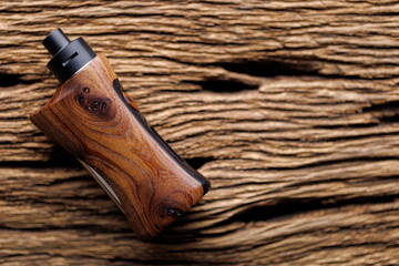 high end rebuildable dripping atomizer with natural stabilized walnut wood regulated box mods on rustic natural wood texture background, vaporizer equipment