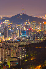 View of Namsan Seoul Tower surrounded by cityscape of Seoul illuminated with lights in the twilight view from Inwang mountain. Seoul, South Korea