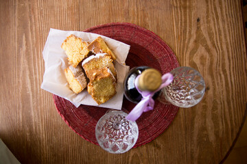 Fototapeta na wymiar top view of a plate with pieces of sponge cake, a bottle of wine and two glasses, on a round tablecloth on a wooden table