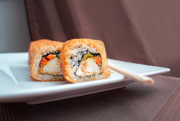 Rollo de suhi en un plato blanco con palillos chinos 