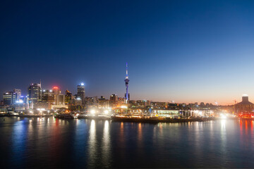 Night city of Auckland New Zealand. Glowing skyscrapers, bay and seaport of Auckland.