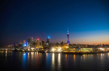 Fototapeta na wymiar Night city of Auckland New Zealand. Glowing skyscrapers, bay and seaport of Auckland.