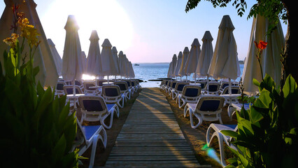 Folded beach umbrellas and sun loungers in the evening on the beach by the sea. Sunset by the sea....