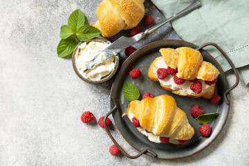Healthy food dessert concept, french pastry. Tasty freshly baked croissants with cream cheese and raspberry on a stone background. View from above. Copy space.
