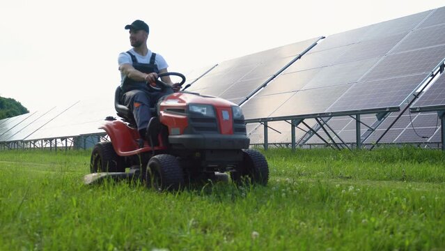 Staff in the solar photovoltaic panels with mowers cut weeds