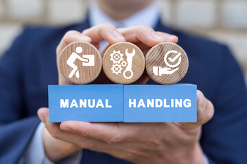 Businessman holding colorful blocks with icons and inscription: MANUAL HANDLING. Concept of manual...