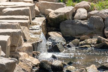 The waterfall flows over the rocks in the stream