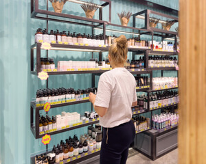 Woman buying make up at cosmetics section in store. choosing cosmetics, perfumes, creams and shampoos, Using tester.