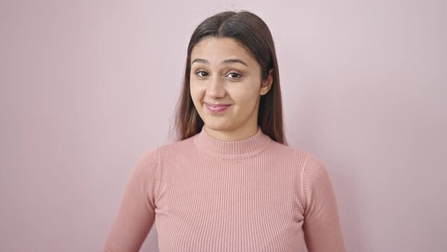 Young beautiful hispanic woman smiling confident saying yes with head over isolated pink background