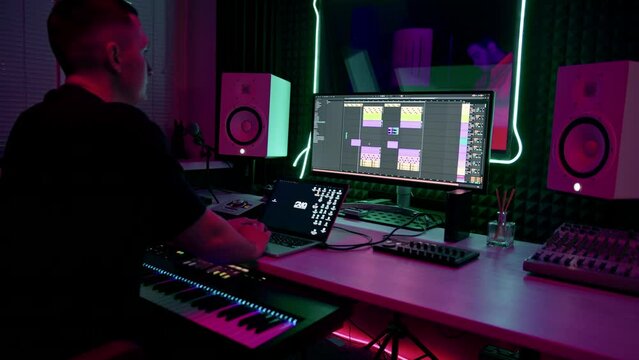 professional sound recording studio sound engineer or music producer sitting at the remote control mixing tracks on the screen neon light