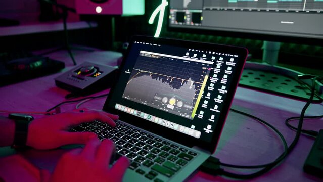 professional sound recording studio sound engineer or music producer sitting at the remote control mixing tracks on the screen neon light