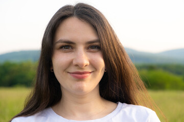 Portrait of a 30-year-old brunette woman looking at the camera smiling in nature.