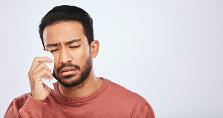 Crying, depression and sad asian man in studio with tissue, crisis or broken heart on grey...