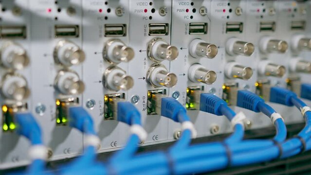 a bunch of patch network cables sorted in a rack cabinet leading from a patch panel in a server rack in a data center room internet cloud storage