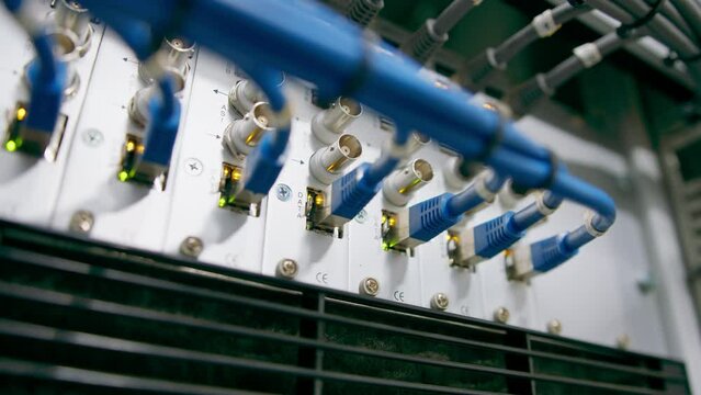 a bunch of patch network cables sorted in a rack cabinet leading from a patch panel in a server rack in a data center room internet cloud storage