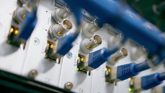 a bunch of patch network cables sorted in a rack cabinet leading from a patch panel in a server rack in a data center room internet cloud storage