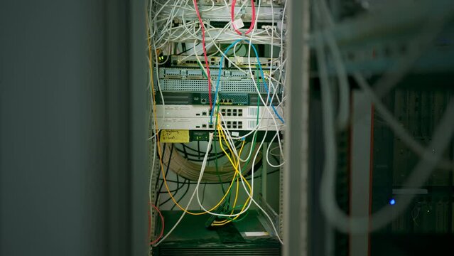 a bunch of patch network cables sorted in a rack cabinet leading from a patch panel in a server rack in a data center room internet cloud storage