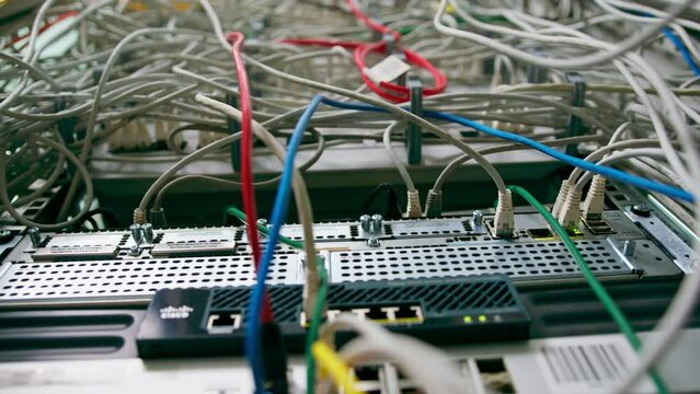 close-up of a pile of network patch cables sorted in a rack cabinet leading from a patch panel in a server rack in a data center room